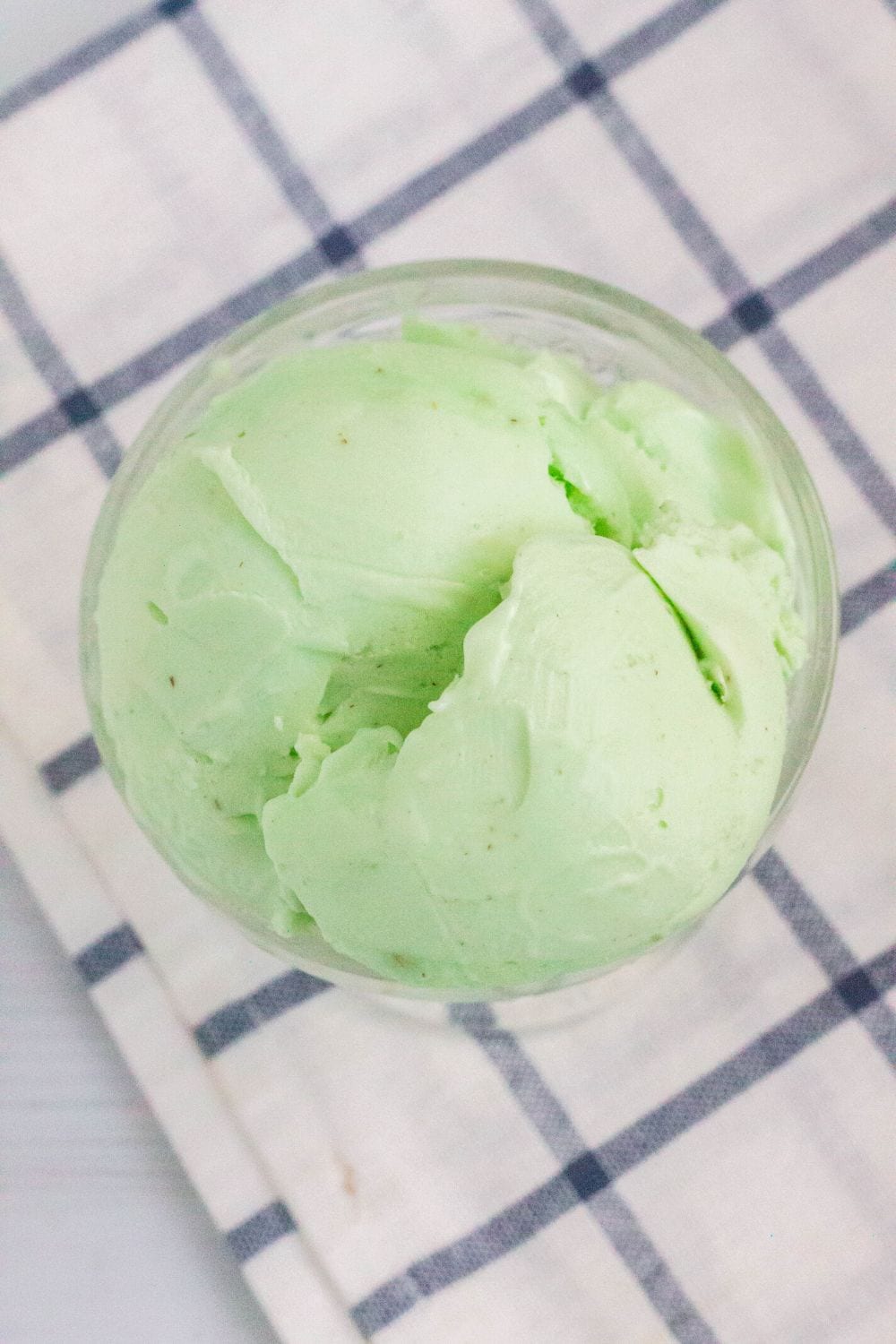 Pistachio ice cream in a bowl on a checkered tablecloth.